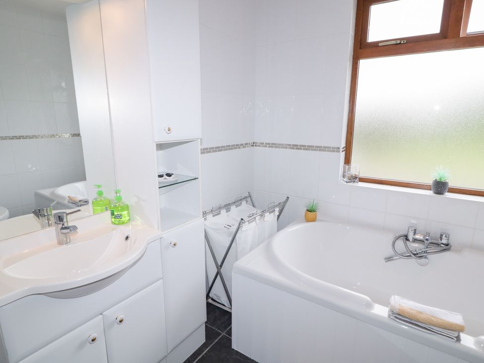 A bathroom with a bathtub, sink, and shelving unit at Ard na Gréine, Glenties, County Donegal