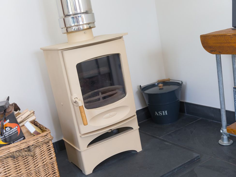 A wood stove with a chimney and ash bucket in a living room at Scilly Stack in Penzance