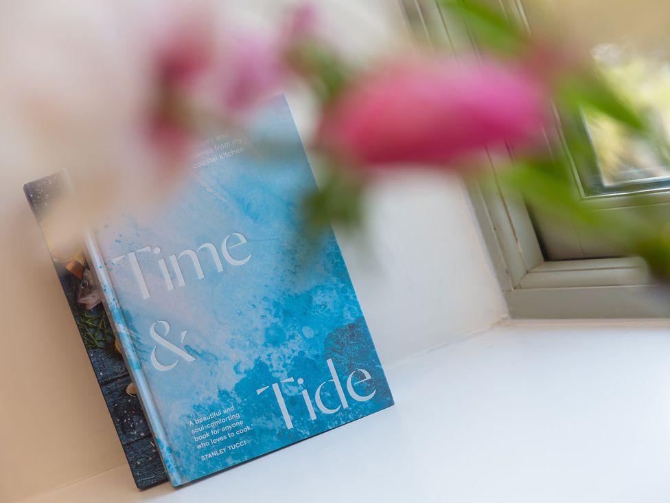 A book on a windowsill with flowers in a vase at Scilly Stack in Penzance