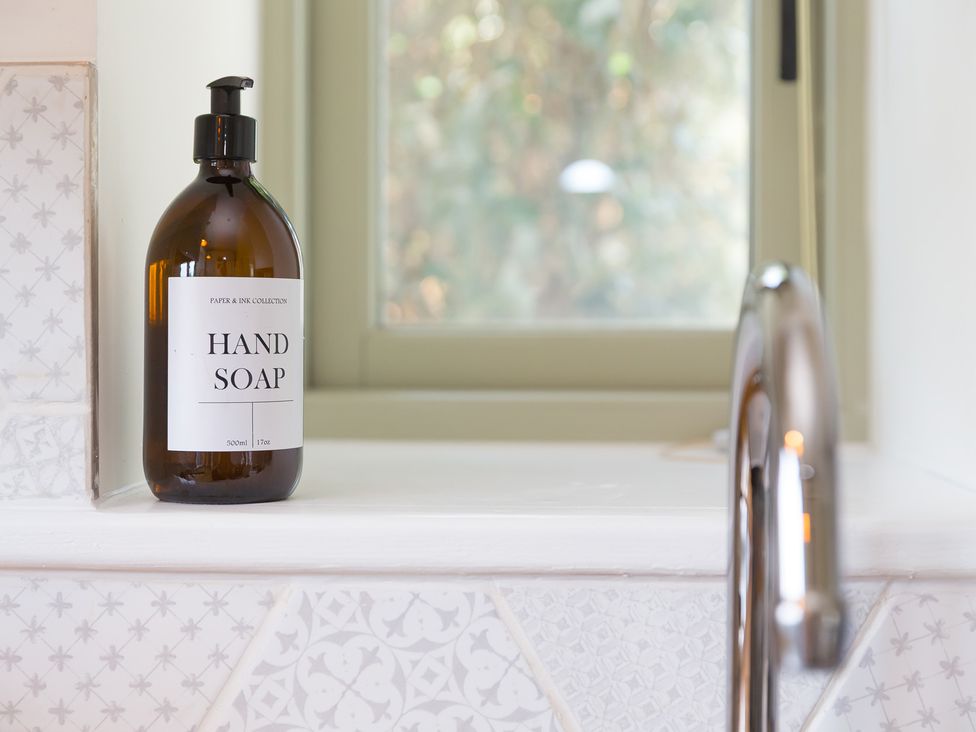 A hand soap bottle and faucet next to a window in a bathroom at Scilly Stack in Penzance
