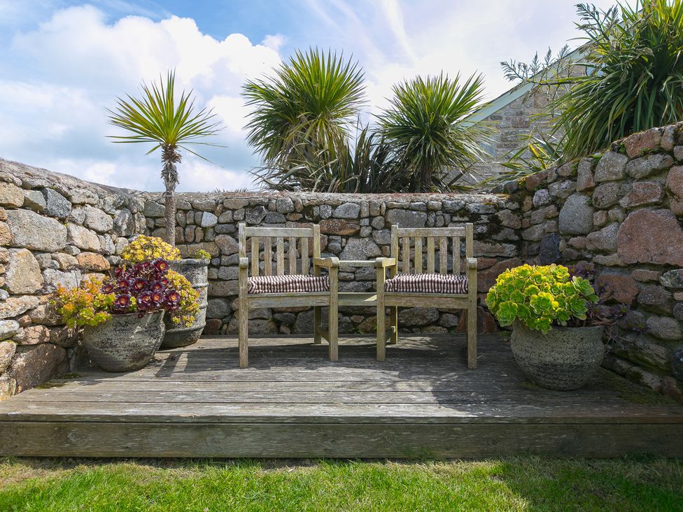 A garden with chairs on a wooden deck at Scilly Stack in Penzance