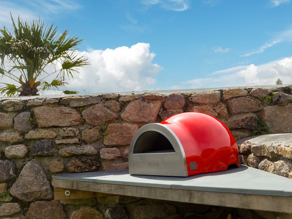 A wood-fired oven on a table next to a stone wall at Scilly Stack in Penzance