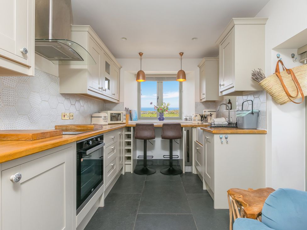 A kitchen with cabinets, countertop, and stools at Scilly Stack in St Just