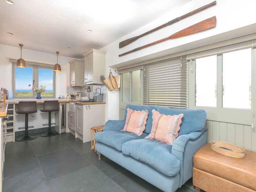 A kitchen with bar stools and a sofa at Scilly Stack in St Just