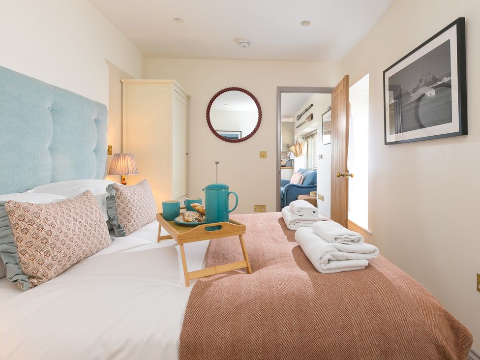 A bedroom with a bed and tray of food at Scilly Stack in St Just