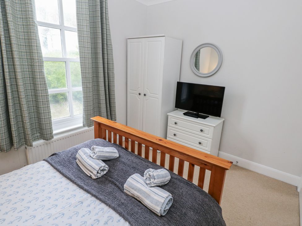 A bedroom with a bed and a television at Crown Cottage in Penally