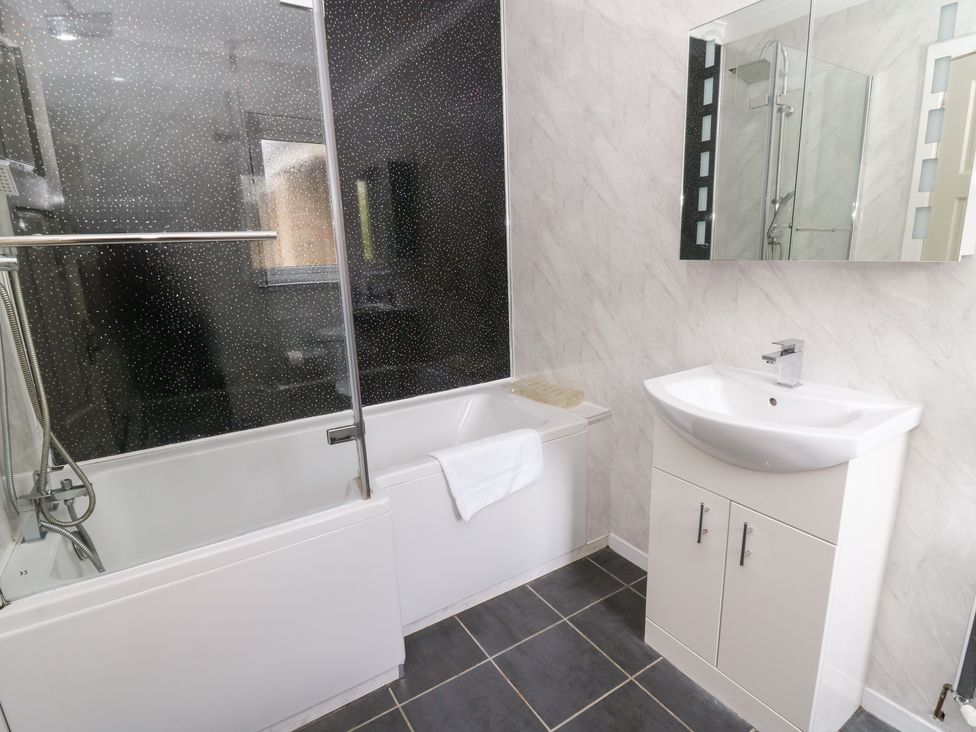 A bathroom with a bathtub and washbasin at Tynewydd Fields in Cross Inn