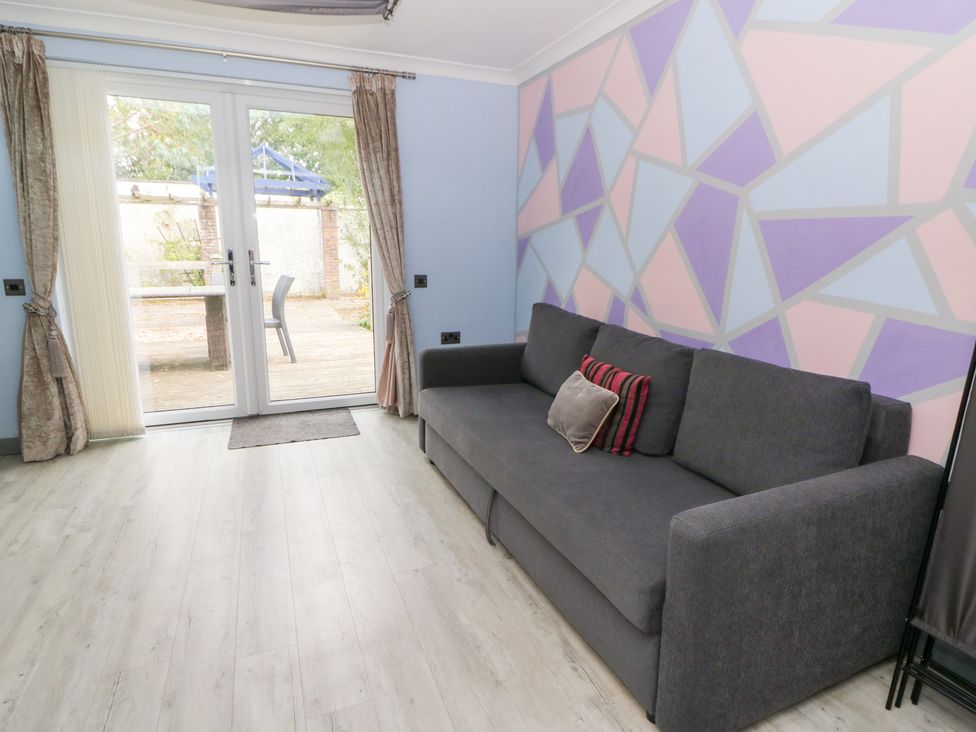 A living room with a sofa and door leading outside at Tynewydd Fields in Cross Inn
