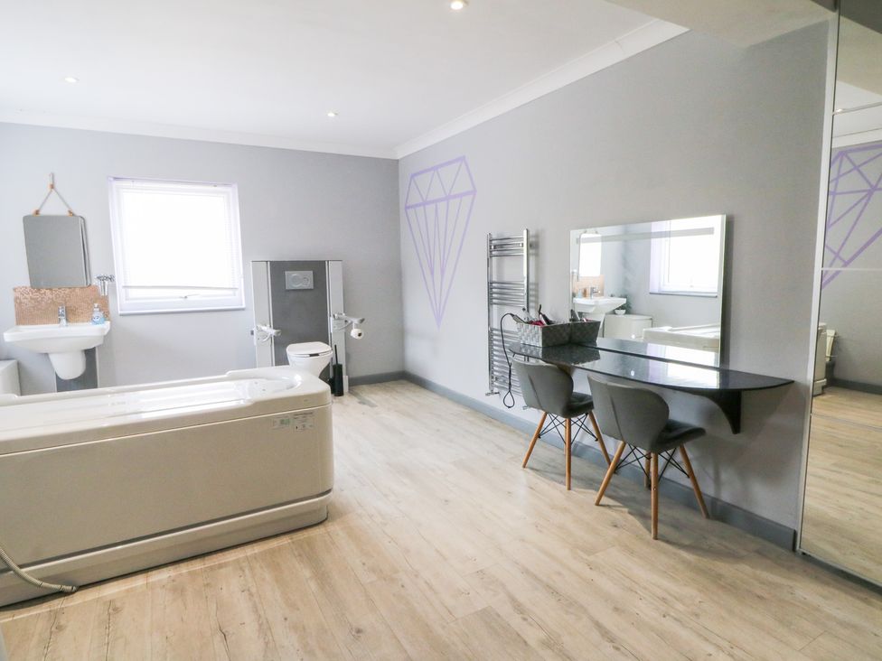 A bathroom with a bathtub, sink, toilet, and mirror at Tynewydd Fields in Cross Inn