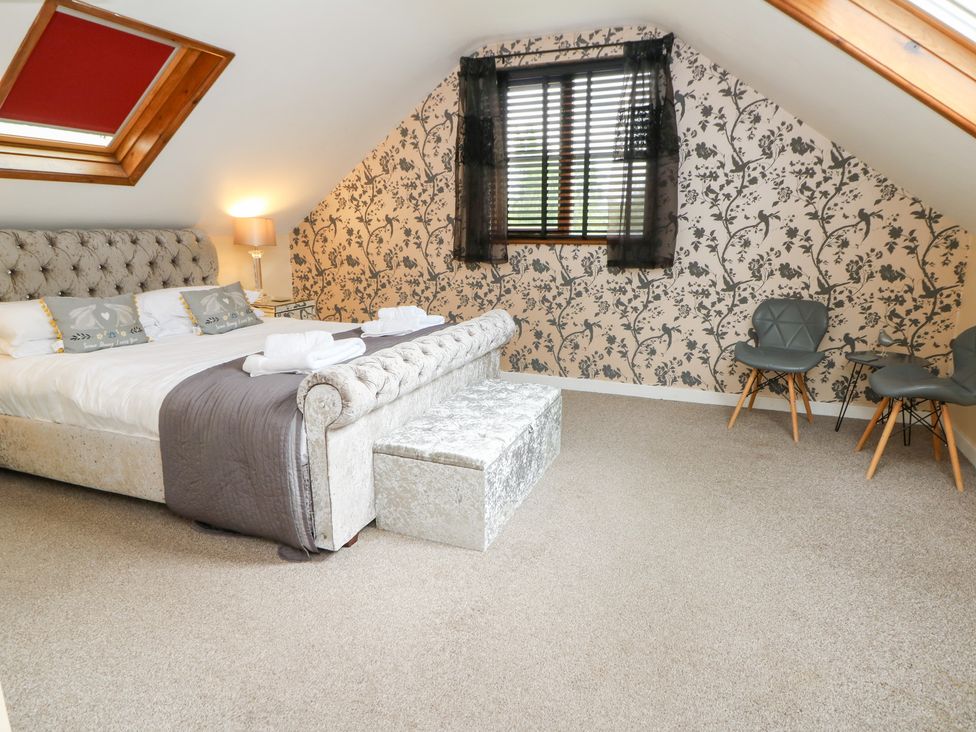 A bedroom with a large bed and seating area at Tynewydd Fields in Cross Inn