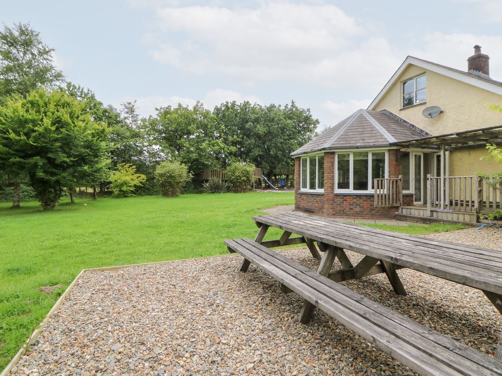 A garden with a house, deck and grassy area at Tynewydd Fields in Cross Inn