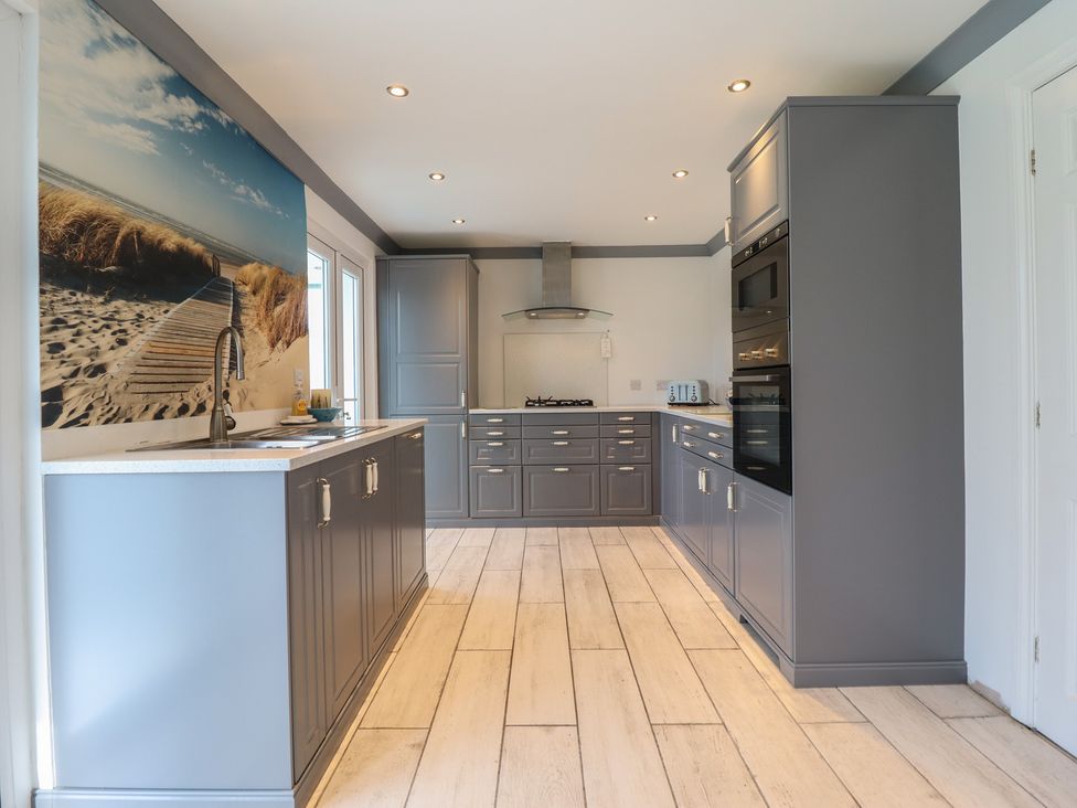 A kitchen with cabinets and appliances at The Beach House in Prestatyn