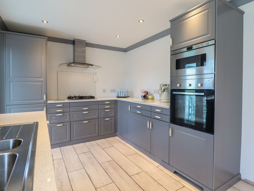 A kitchen with cabinets, oven, stove, and sink at The Beach House in Prestatyn