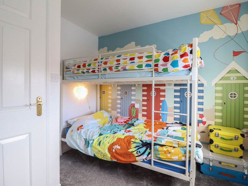 A bedroom with a bunk bed and colorful linens at The Beach House in Prestatyn