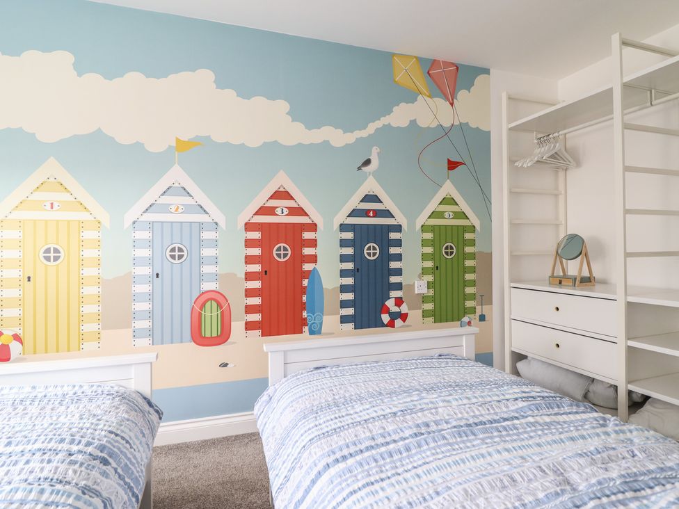 A bedroom with beach huts wallpaper and two beds at The Beach House in Prestatyn