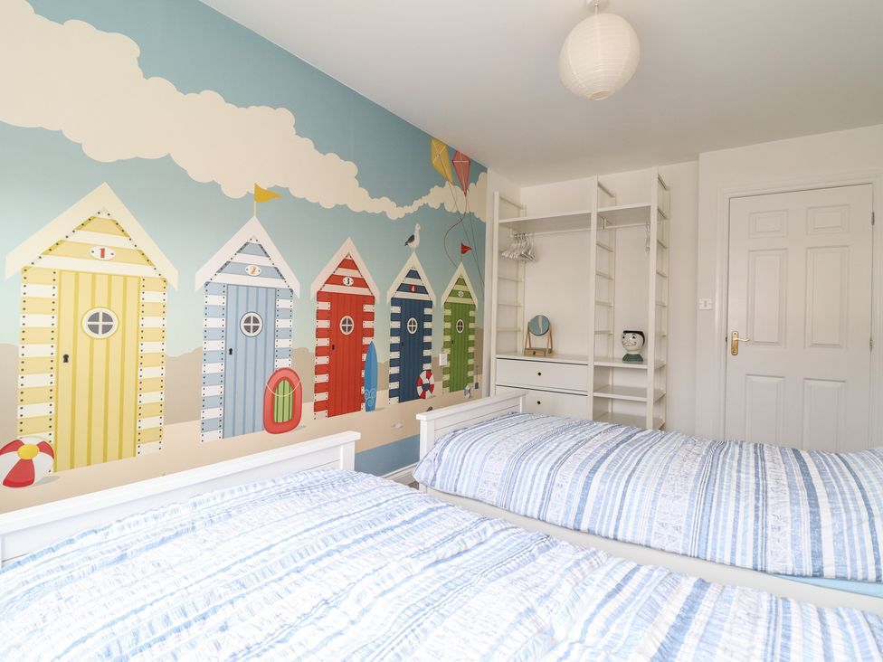 A bedroom with two beds and a beach hut mural at The Beach House in Prestatyn
