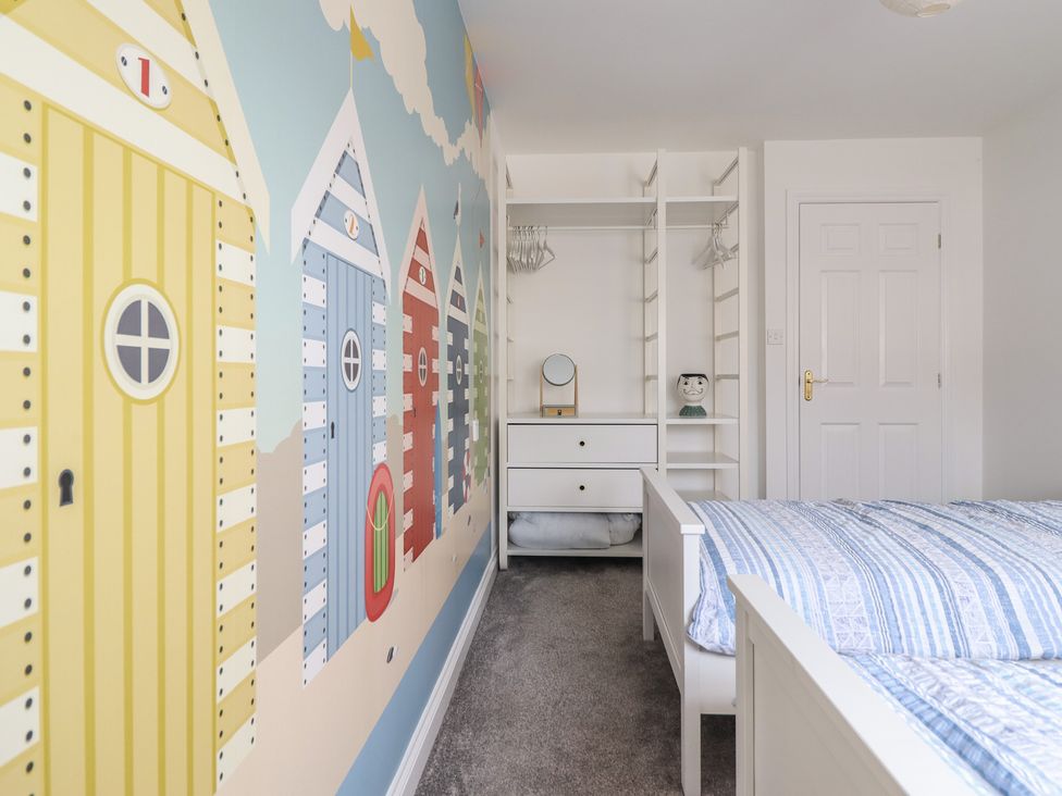 A bedroom with a bed and storage at The Beach House in Prestatyn