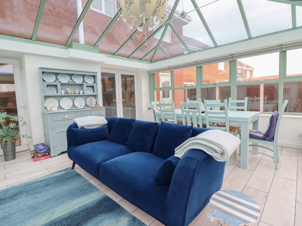 A conservatory with a sofa and dining area at The Beach House in Prestatyn