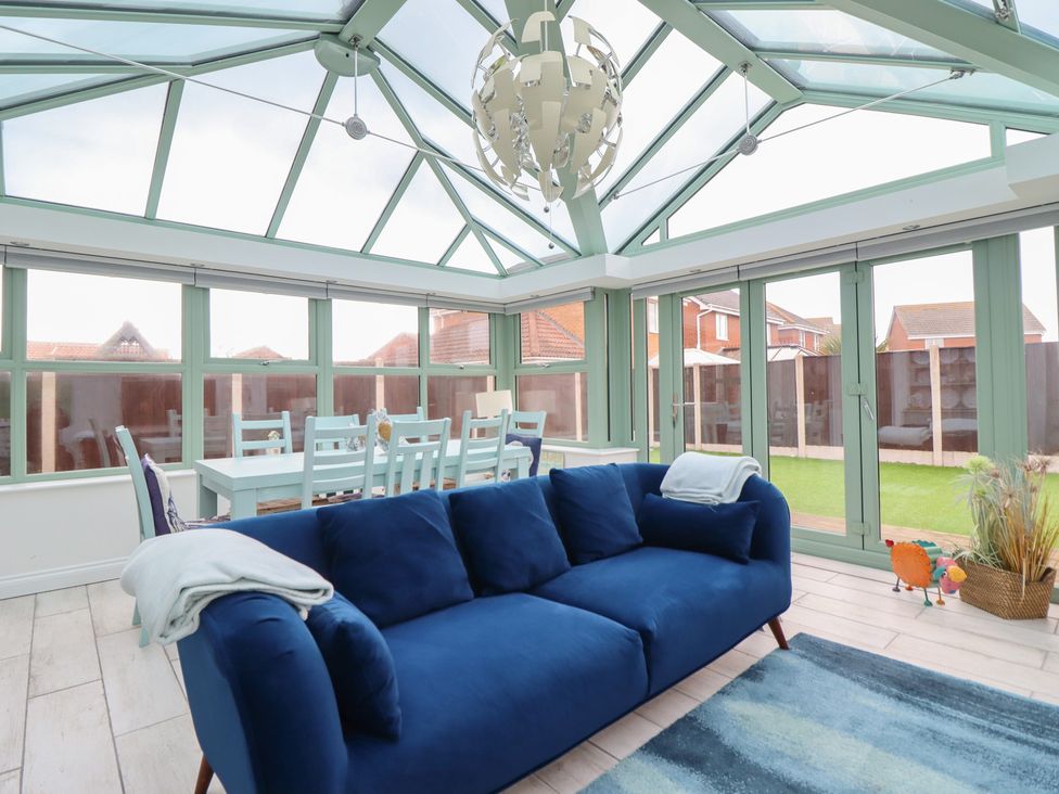 A conservatory with a sofa and dining table at The Beach House in Prestatyn