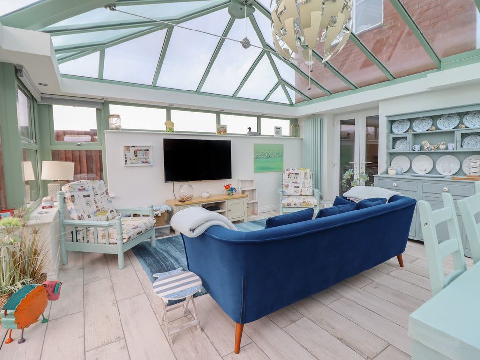 A conservatory with seating and a television at The Beach House in Prestatyn