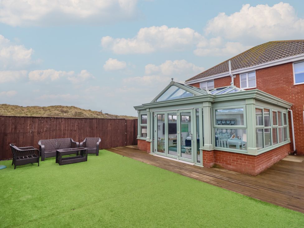A conservatory with seating area on grass at The Beach House in Prestatyn