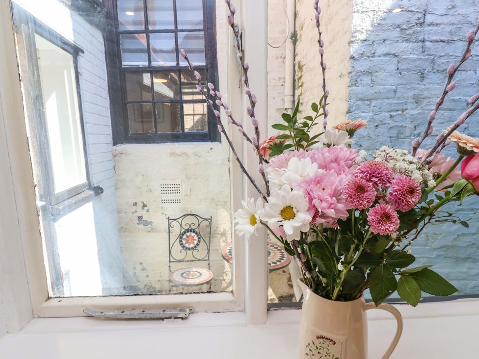 A window with flowers in a vase and a view of a table and chair at The Anchorage in Whitby