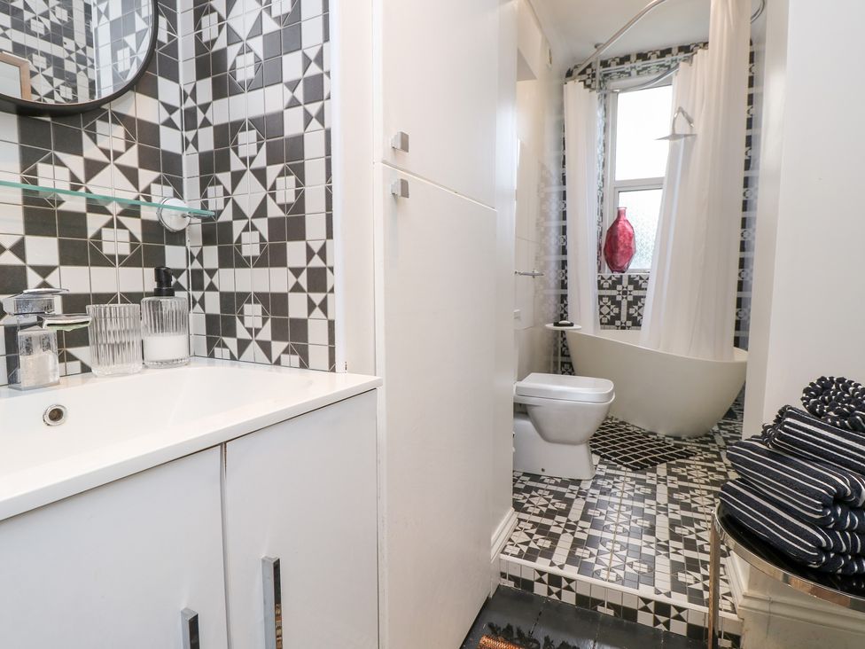 A bathroom with a sink, toilet, bathtub, and patterned tiles at No. 5 Cliffview, Ventnor