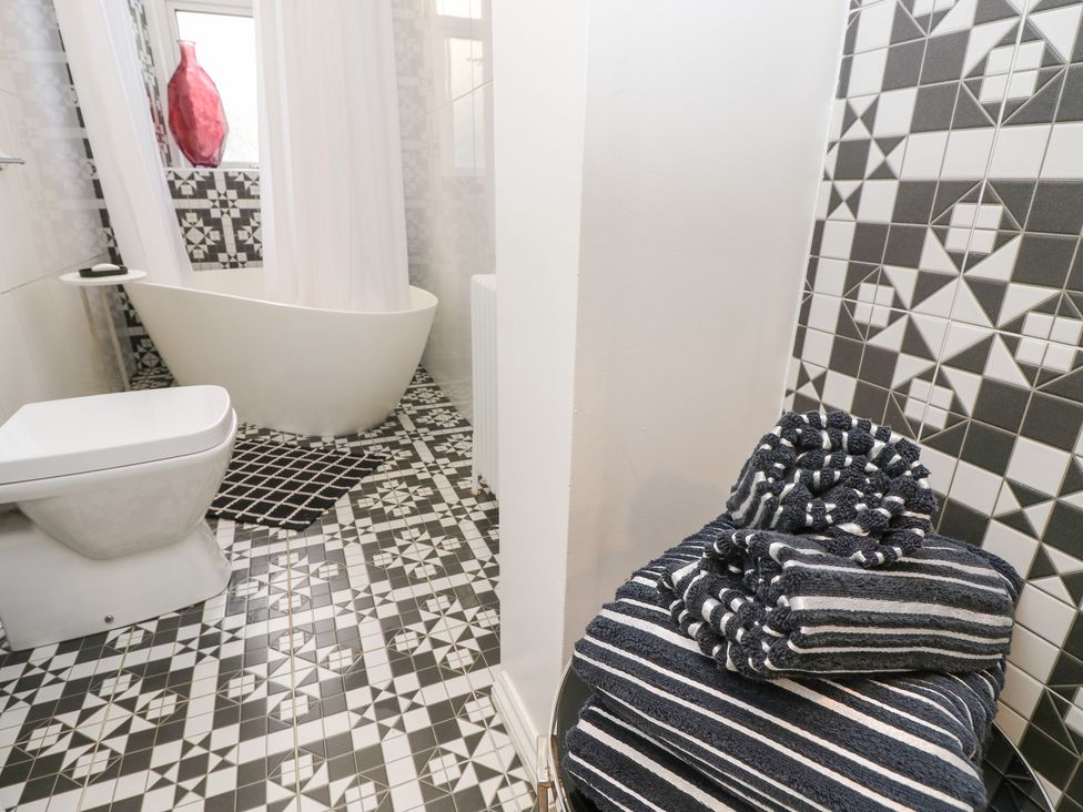 A bathroom featuring a bathtub, toilet, and towels at No. 5 Cliffview Ventnor