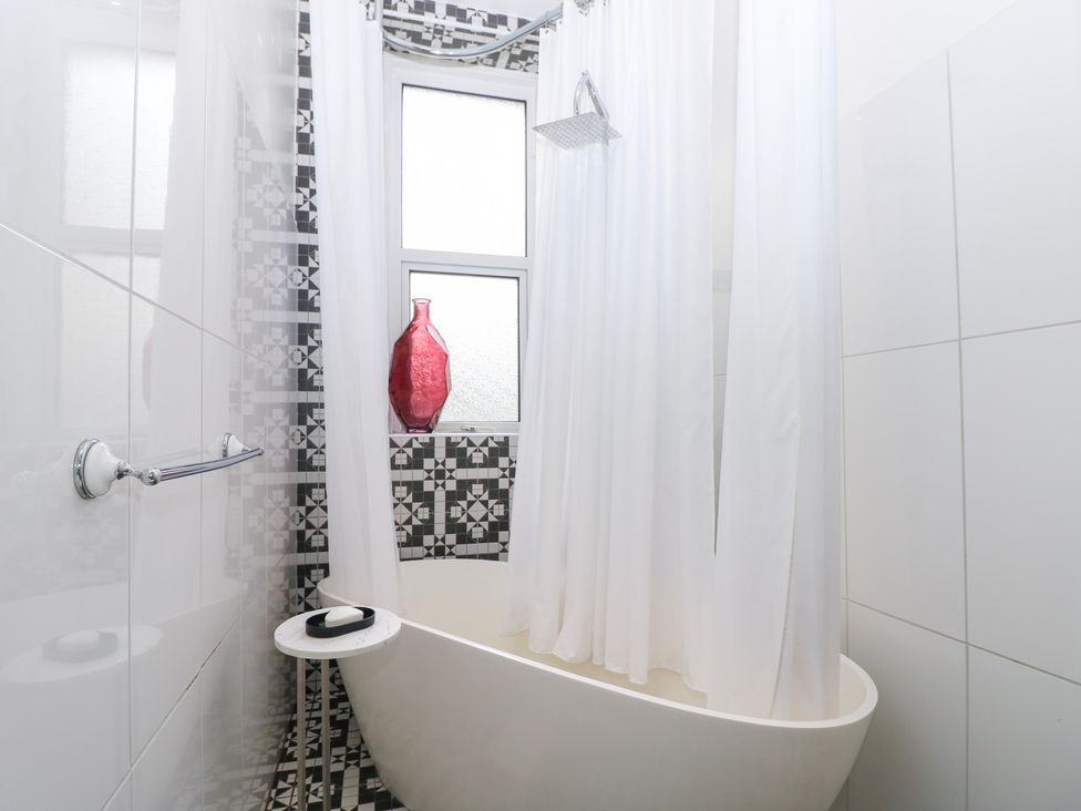 A bathroom with a bathtub and shower setup at No. 5 Cliffview, Ventnor