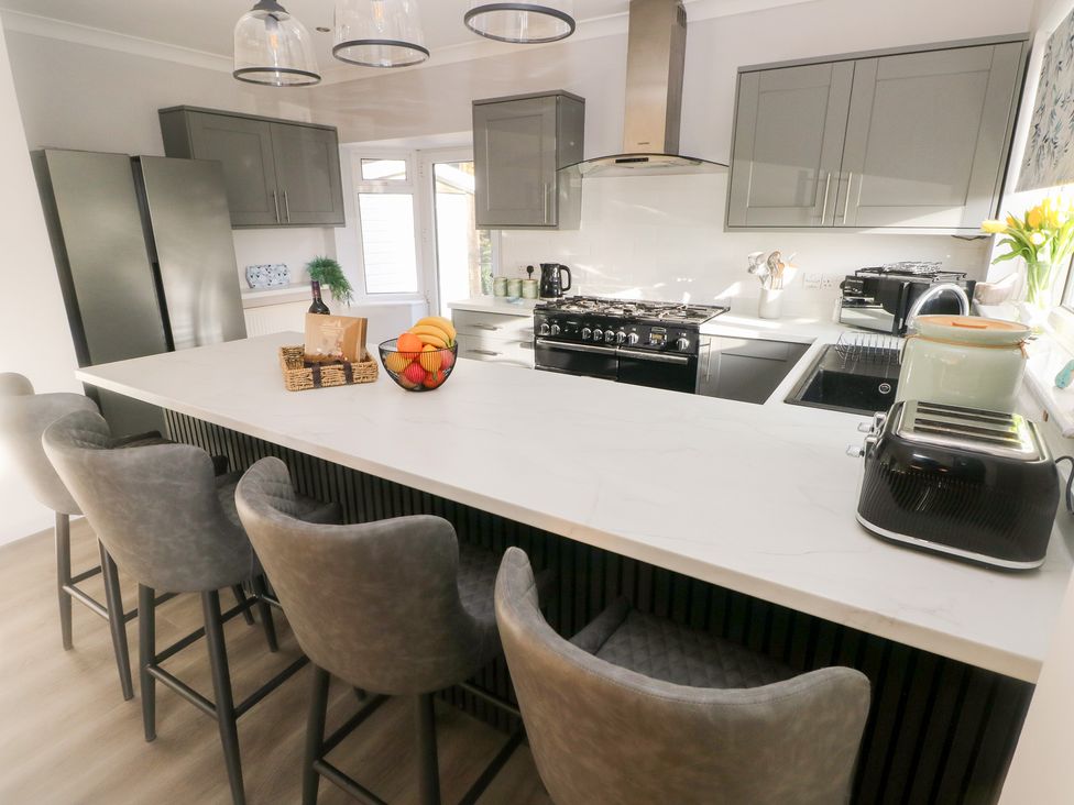 A kitchen with a kitchen island and bar stools at Westwinds in Tenby