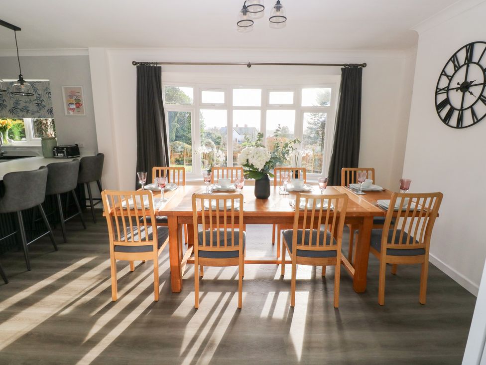 A dining room with a wooden table and chairs at Westwinds in Tenby