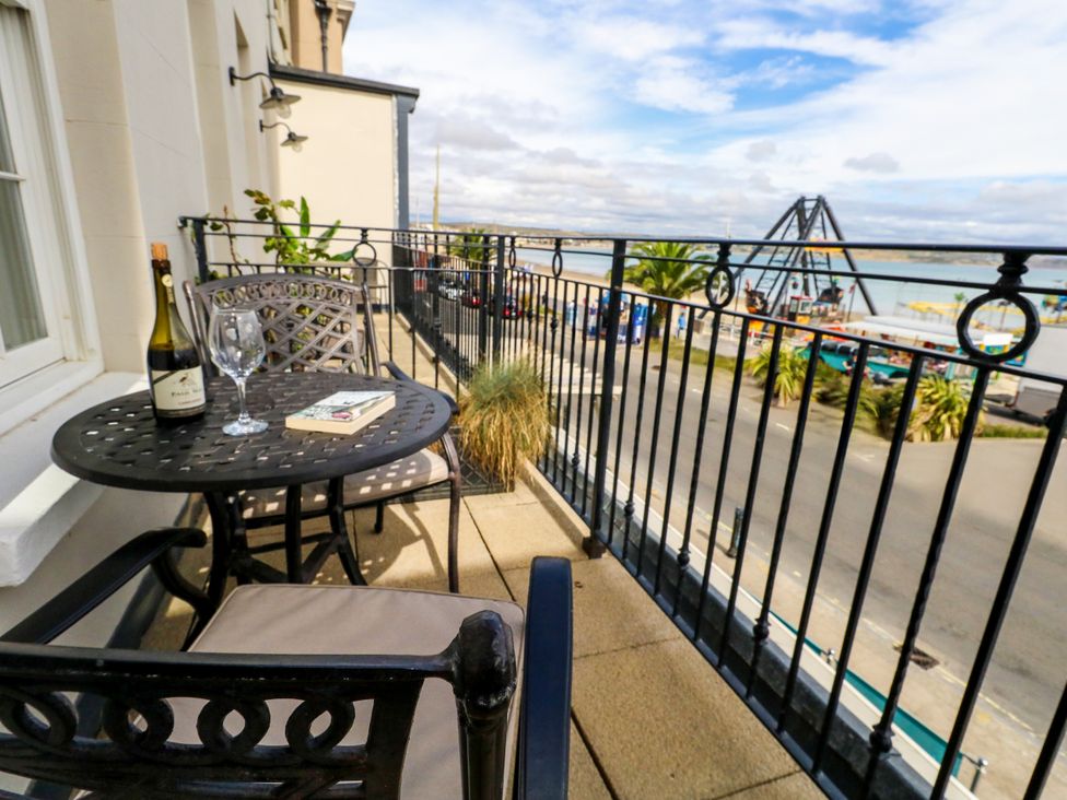 A balcony with a table and chairs overlooking the waterfront at 4 The Beaches Weymouth