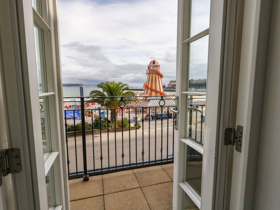 A balcony view overlooking a beach with palm trees at 4 The Beaches Weymouth