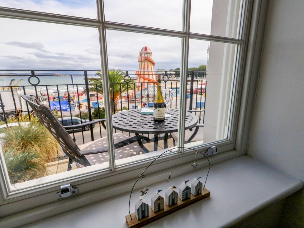 A window view showing a table with a bottle and beach outside at 4 The Beaches Weymouth