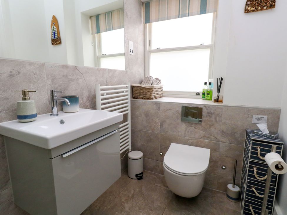 A bathroom featuring a sink, toilet, and towel storage at 4 The Beaches in Weymouth