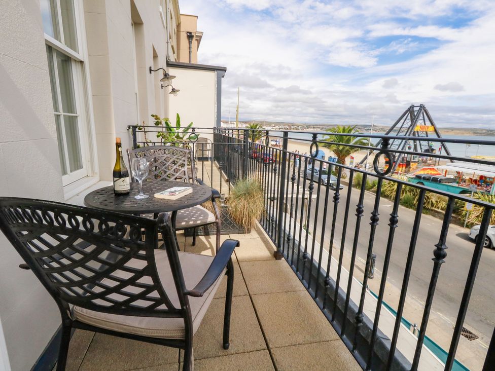 A balcony with a table and chairs overlooking a street at 4 The Beaches Weymouth