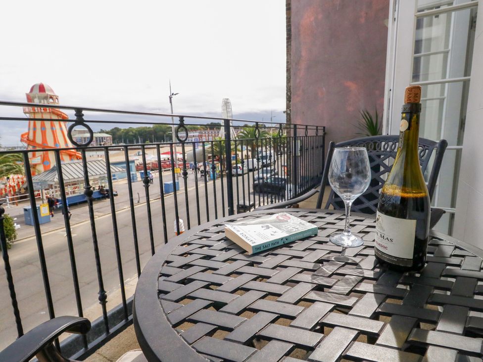 A balcony with a bottle of wine and a glass overlooking a view at 4 The Beaches Weymouth