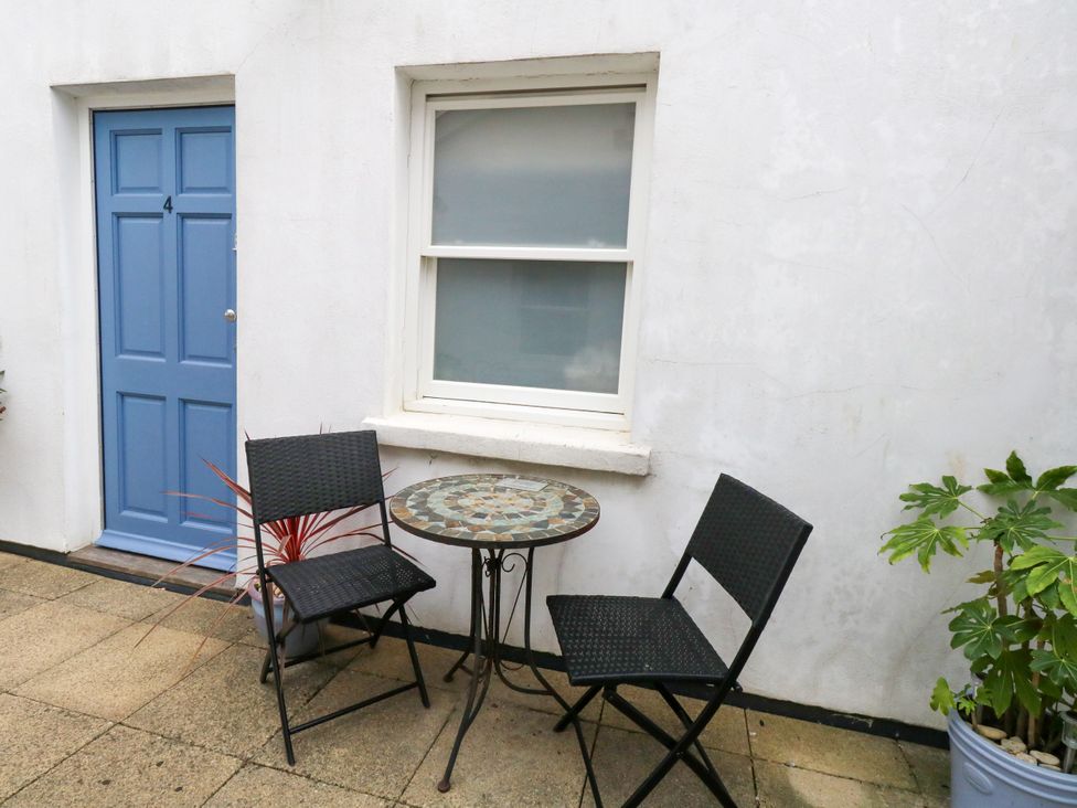 An outdoor area with a table and chairs in front of a door and window at 4 The Beaches in Weymouth