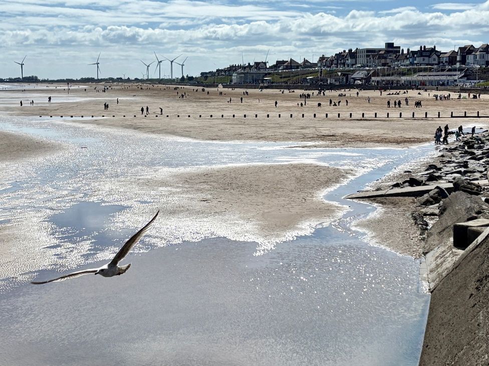 A beach with people and wind turbines at Bobbies Retreat, 20 High Street, Bridlington