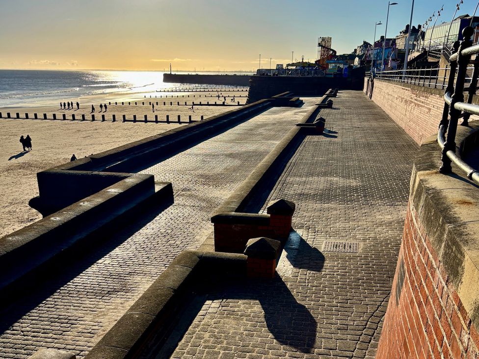 A beach with pavement and people walking at Bobbies Retreat, 20 High Street, Bridlington