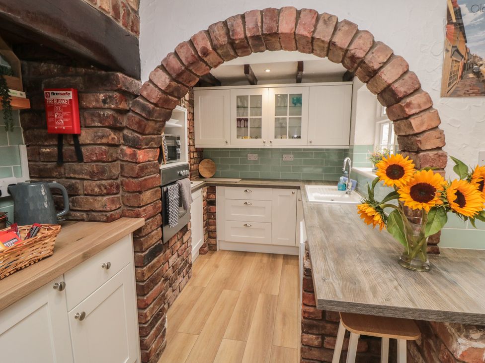 A kitchen with an archway and flowers on the table at Bobbies' Retreat, 20 High Street, Bridlington