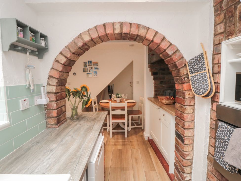 A kitchen with archway leading to dining space at Bobbies' Retreat, 20 High Street, Bridlington