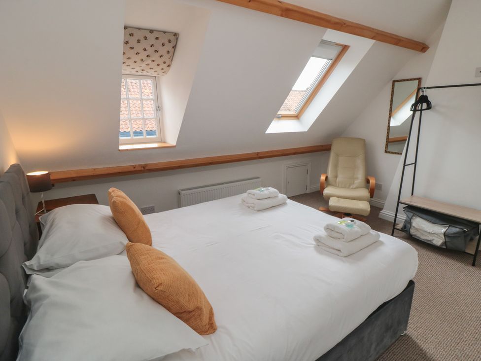 A bedroom with a bed, nightstand, armchair, and window at Bobbies' Retreat, 20 High Street Bridlington