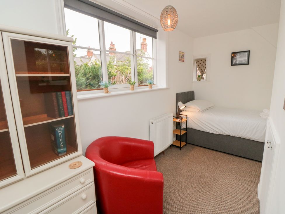 A bedroom with a bed, bookshelf and armchair at Bobbies Retreat, 20 High Street, Bridlington