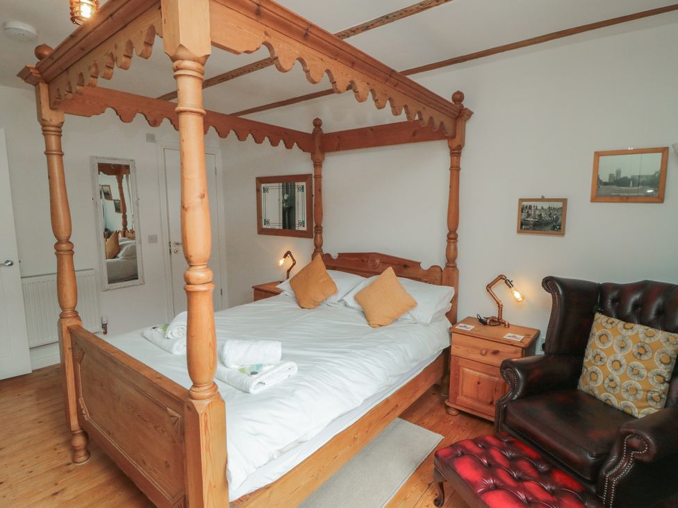 A bedroom with a four-poster bed and armchair at Bobbies Retreat, 20 High Street, Bridlington