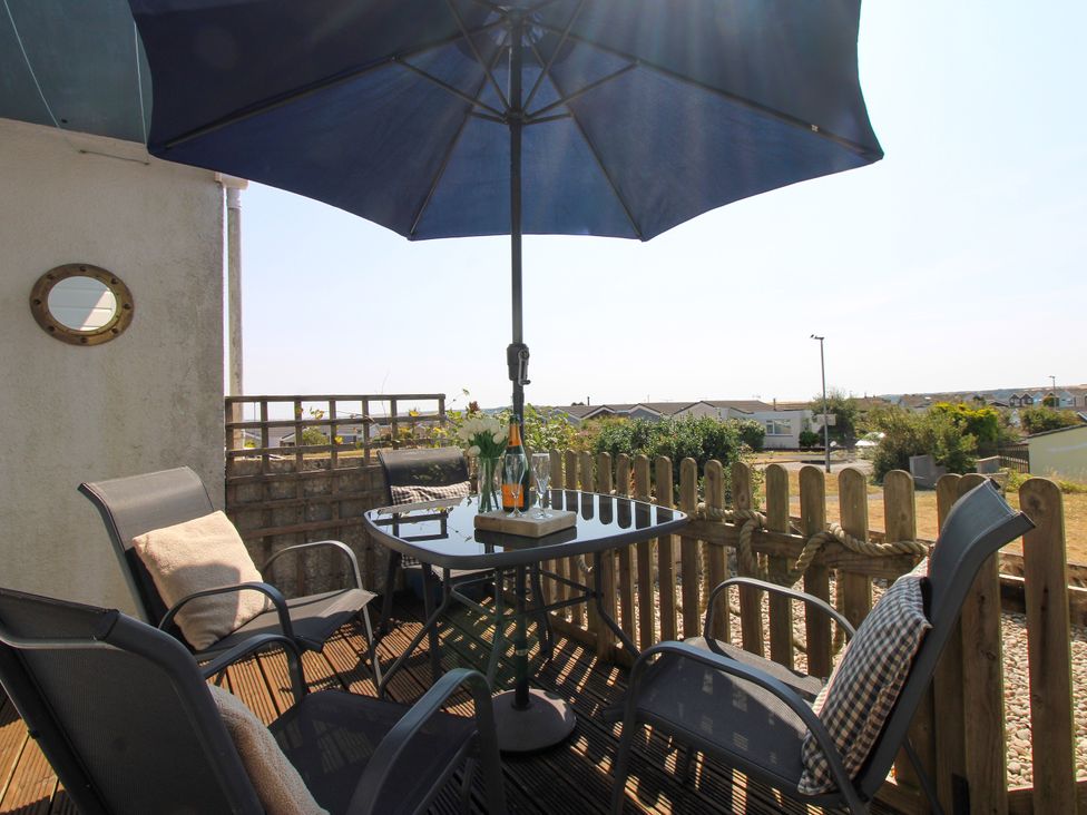 A patio with a table and chairs at Merlin in Malborough