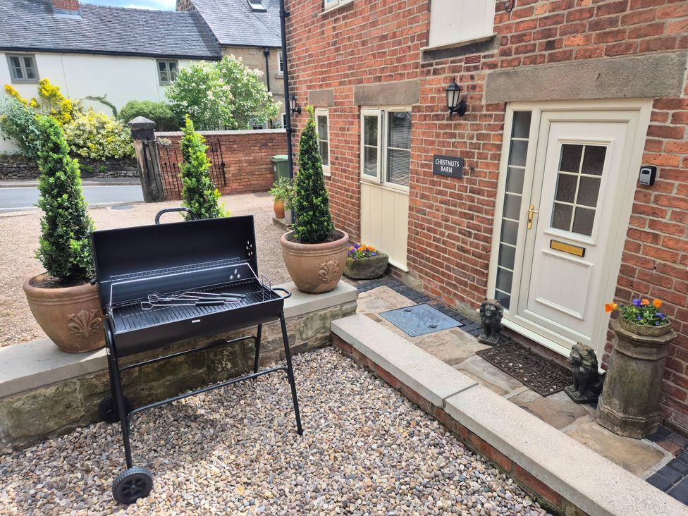An outdoor area with a barbecue grill and planters at Chestnuts Barn in Holbrook, Derbyshire