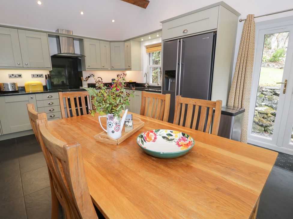 A kitchen with a dining table and refrigerator at Greffyn in Betws-Y-Coed