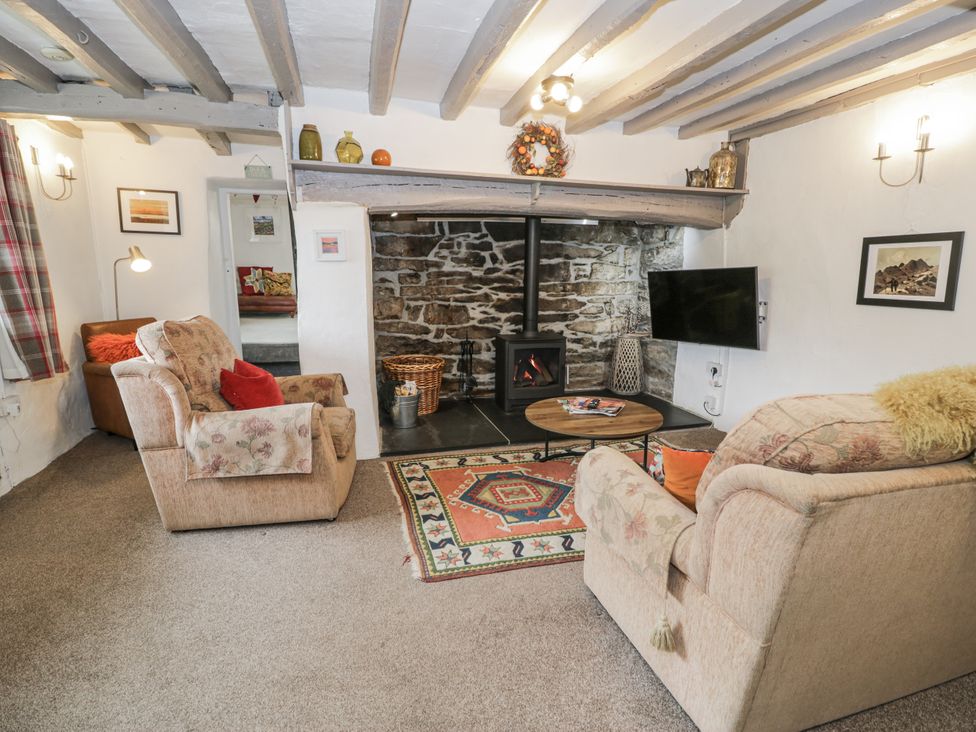 A living room with a fireplace and seating at Orsedd Wen Farmhouse in Betws-Y-Coed