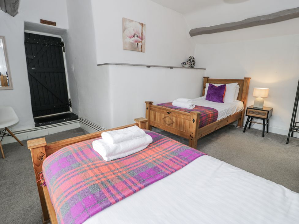 A bedroom with two beds and a door at Orsedd Wen Farmhouse in Betws-Y-Coed